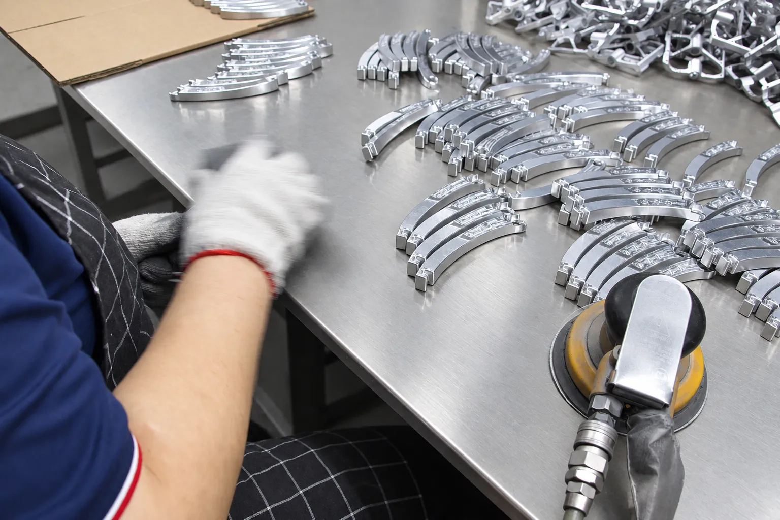 An operator deburring machined aluminum parts with a pneumatic tool at a finishing bench